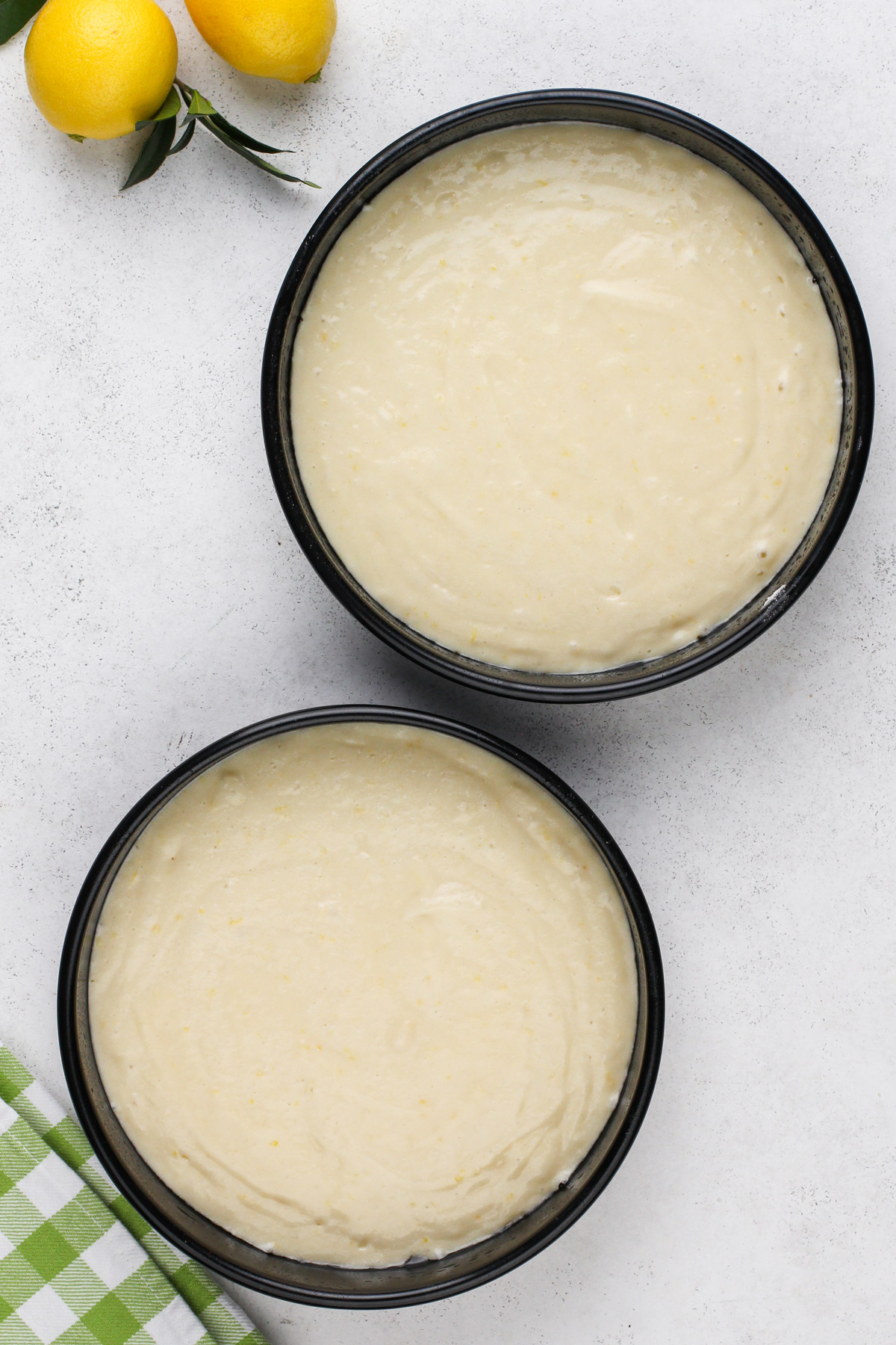 Unbaked lemon cake batter divided between two cake pans.